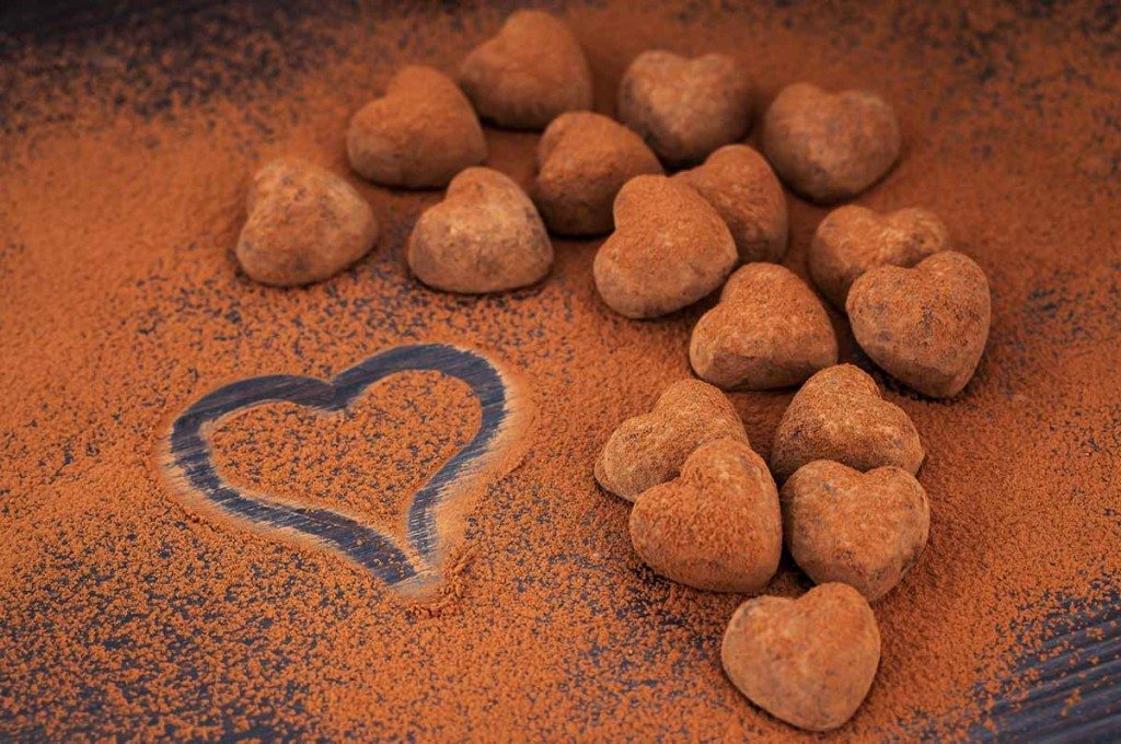 Heart shaped chocolate truffles on cocoa powdered table.