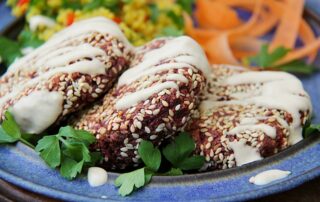 Beetroot burgers on a plate with tahini sauce and salad
